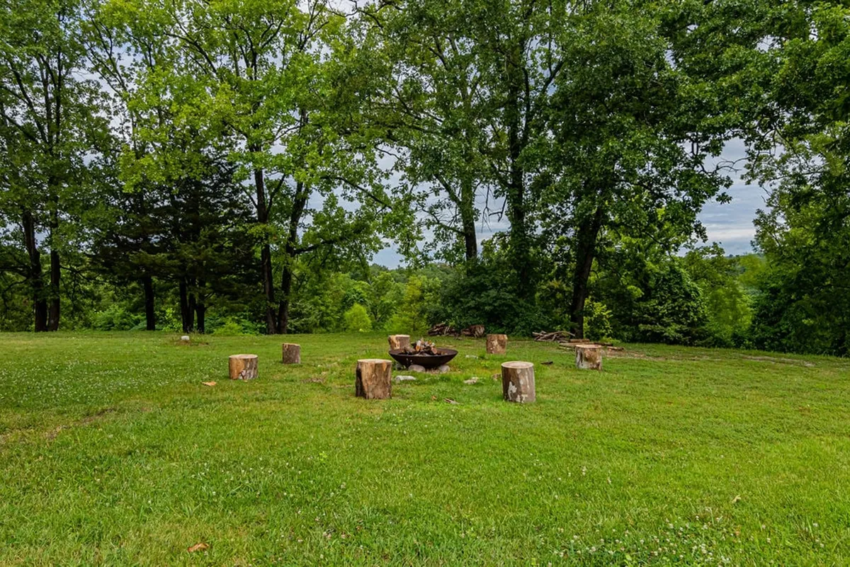 An outdoor fire pit area with log seating encircled by trees, creating an inviting communal space for campfires, storytelling, and stargazing. The setup encourages social gatherings and relaxation after a day of adventure.