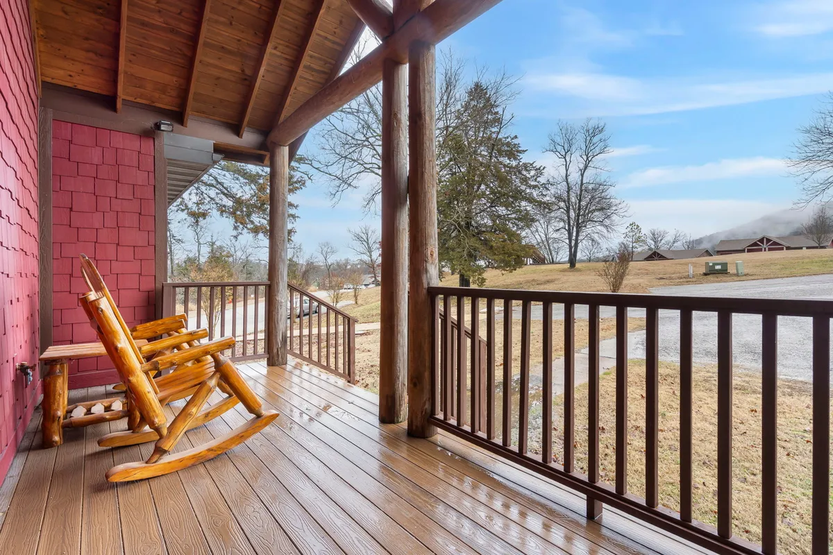 This image features a wooden deck with classic rocking chairs and a view of the surrounding landscape. The scene is relaxed and peaceful, showing a perfect spot for enjoying coffee in the morning or unwinding in the evening.