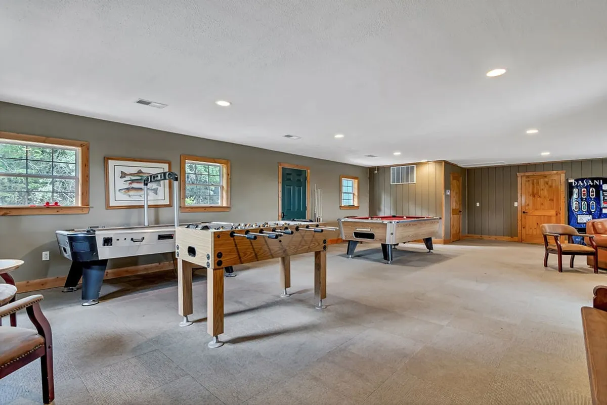 An interior view of the Tad Pools Activity Center, showcasing a foosball table, pool table, and a comfortable seating area with ample natural light. The space is designed for socializing, playing games, and unwinding after a day of outdoor activities.